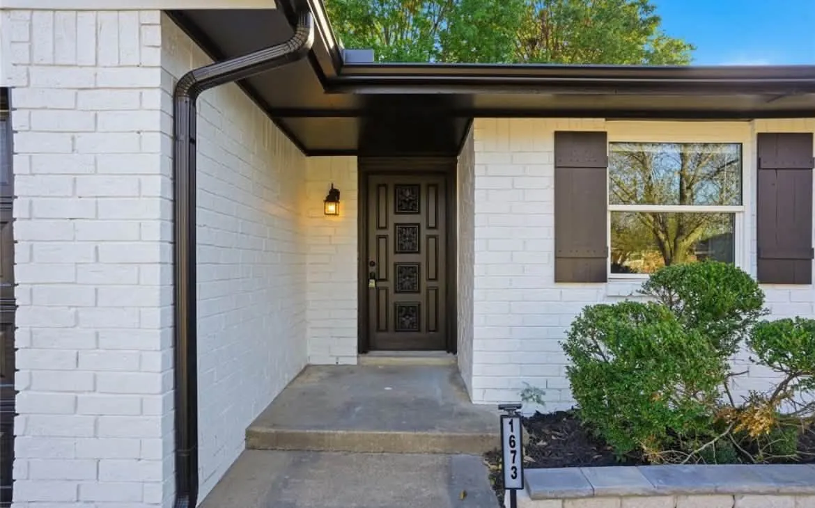 Painted white brick entry with dark stained front door and shutters