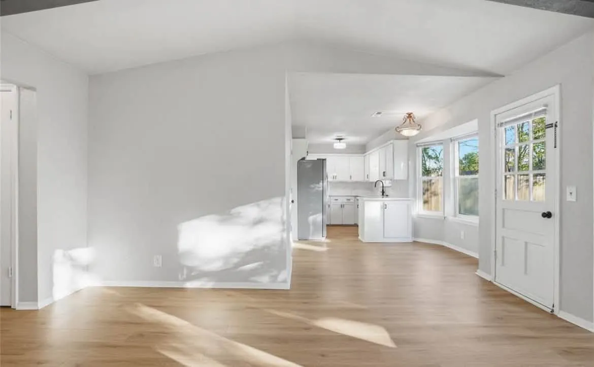 Freshly painted gray living room with vaulted ceiling and white trim